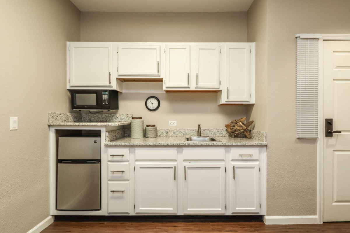 A small kitchen with white cabinets, a microwave, and a sink.