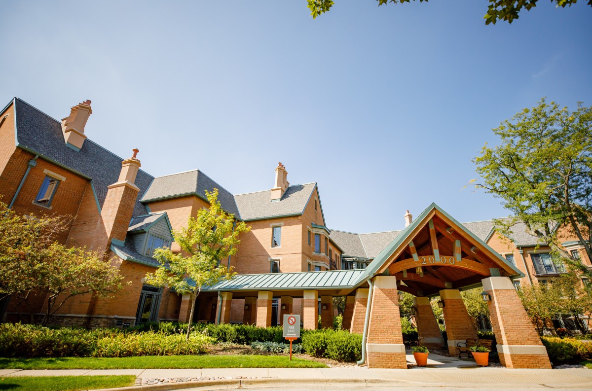 A beautiful brick building with a sloped roof and inviting entrance, surrounded by greenery.