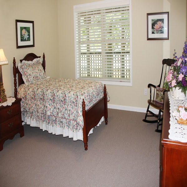 A cozy bedroom with a single bed, traditional wooden furniture, and a rocking chair.