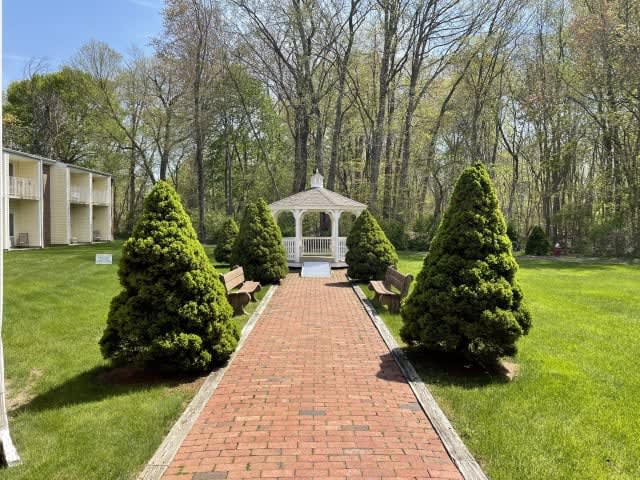 A scenic pathway leading to a charming gazebo surrounded by lush greenery.