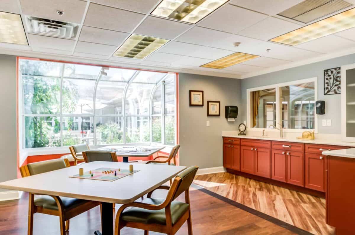 A bright, inviting dining area with a kitchenette and large windows allowing natural light to fill the space.