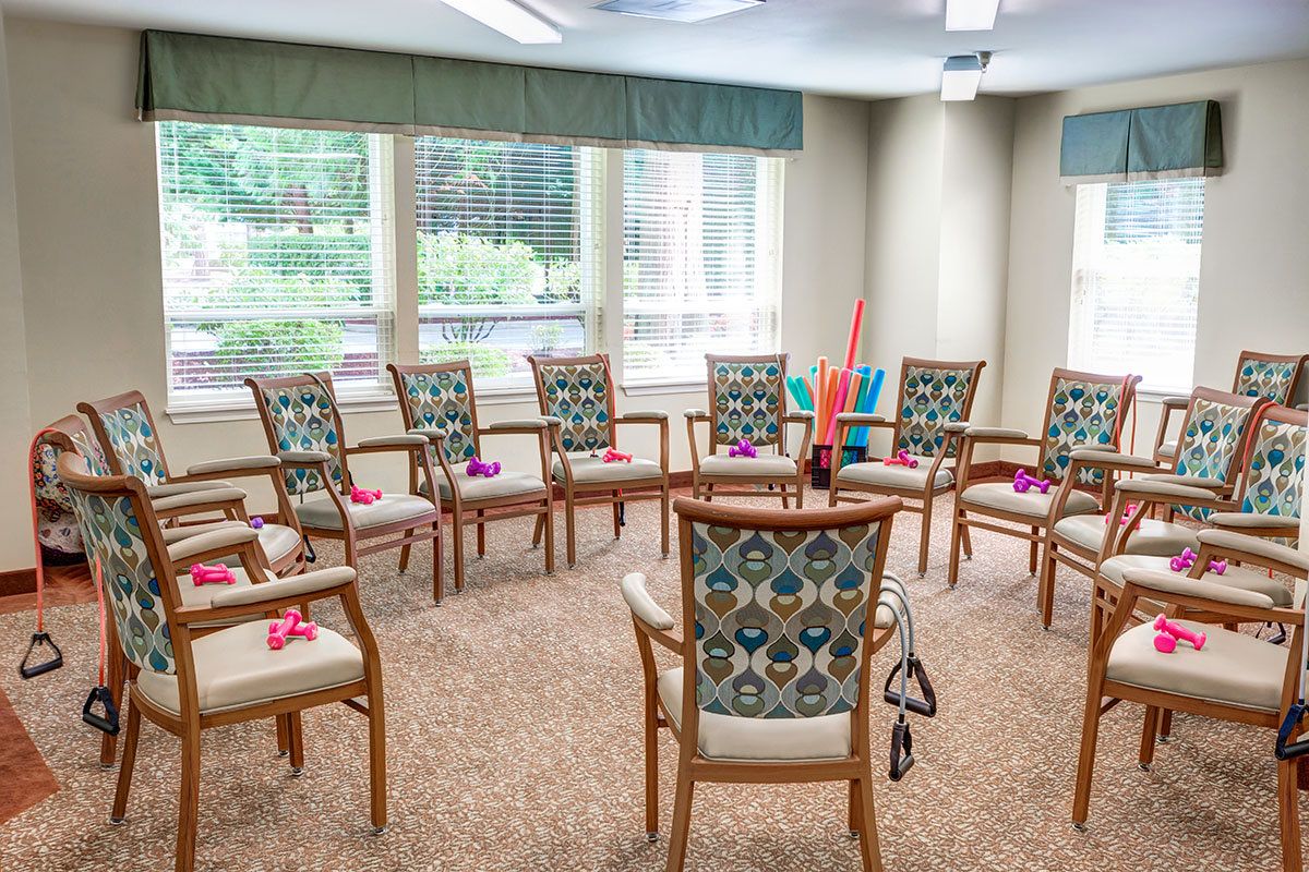 A meeting room with chairs arranged in a circle, featuring decorative flowers on each chair and large windows providing natural light.