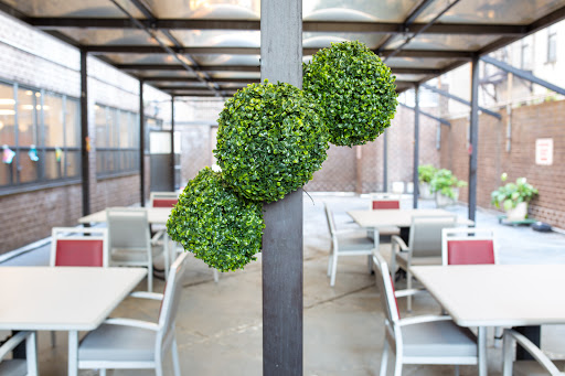 A modern dining area featuring decorative artificial greenery clusters mounted on a pole.