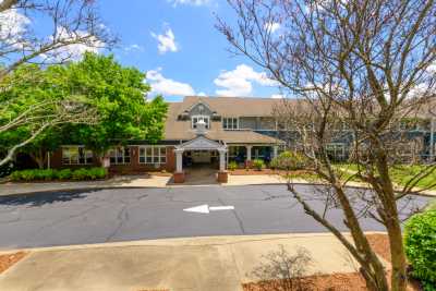 A two-story building with an entrance surrounded by trees and a driveway under a blue sky.