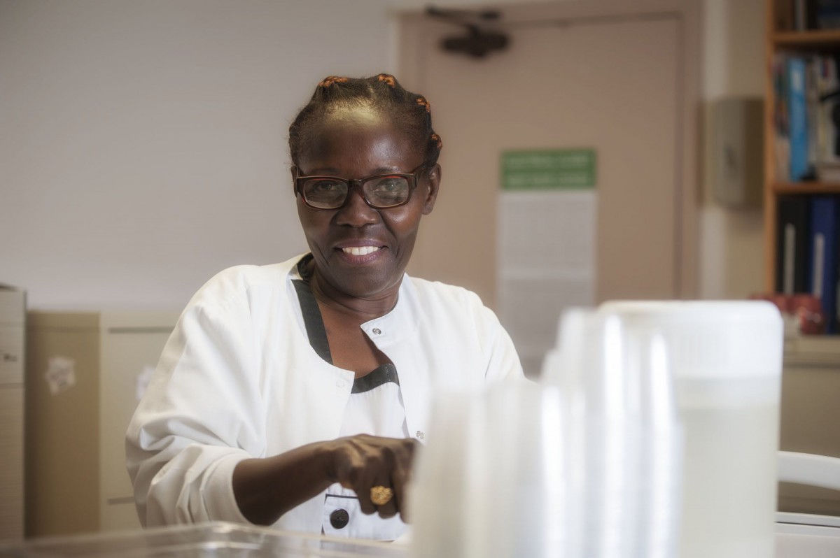 A smiling woman wearing glasses and a white coat indoors.
