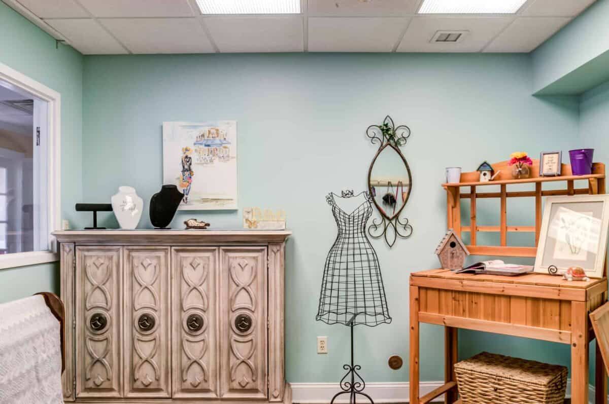 A stylish interior with a decorative mannequin, vintage furniture, and wall art.