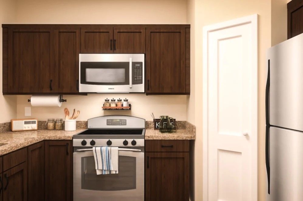 A modern kitchen with brown cabinets, featuring a stainless steel stove and microwave.