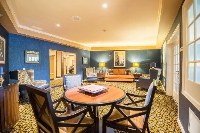 A cozy and elegant living room featuring a seating area with a round table, comfortable chairs, a sofa, and ambient lighting.