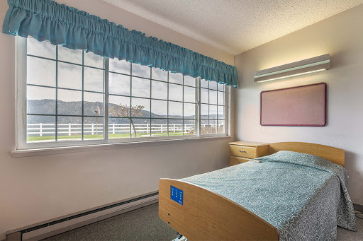 A serene hospital room featuring a single bed and large windows overlooking a scenic view.