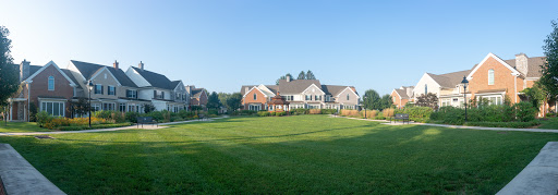 A picturesque view of modern homes set against a clear blue sky, featuring a lush green lawn.