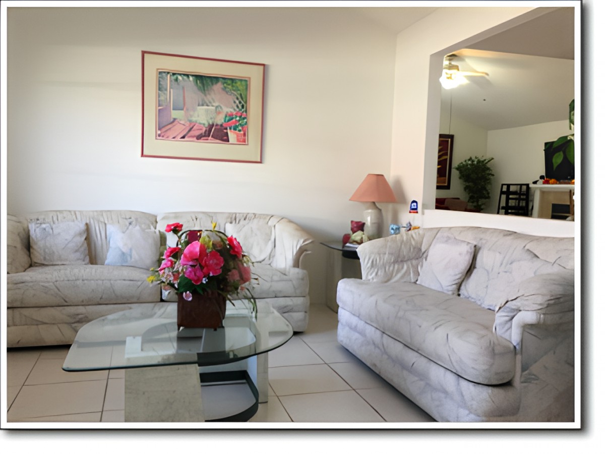 A cozy living room with comfortable sofas, a glass coffee table, and colorful decor.