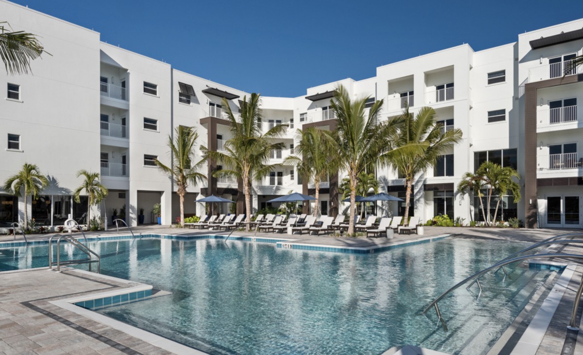 A luxurious hotel with a large swimming pool surrounded by palm trees.