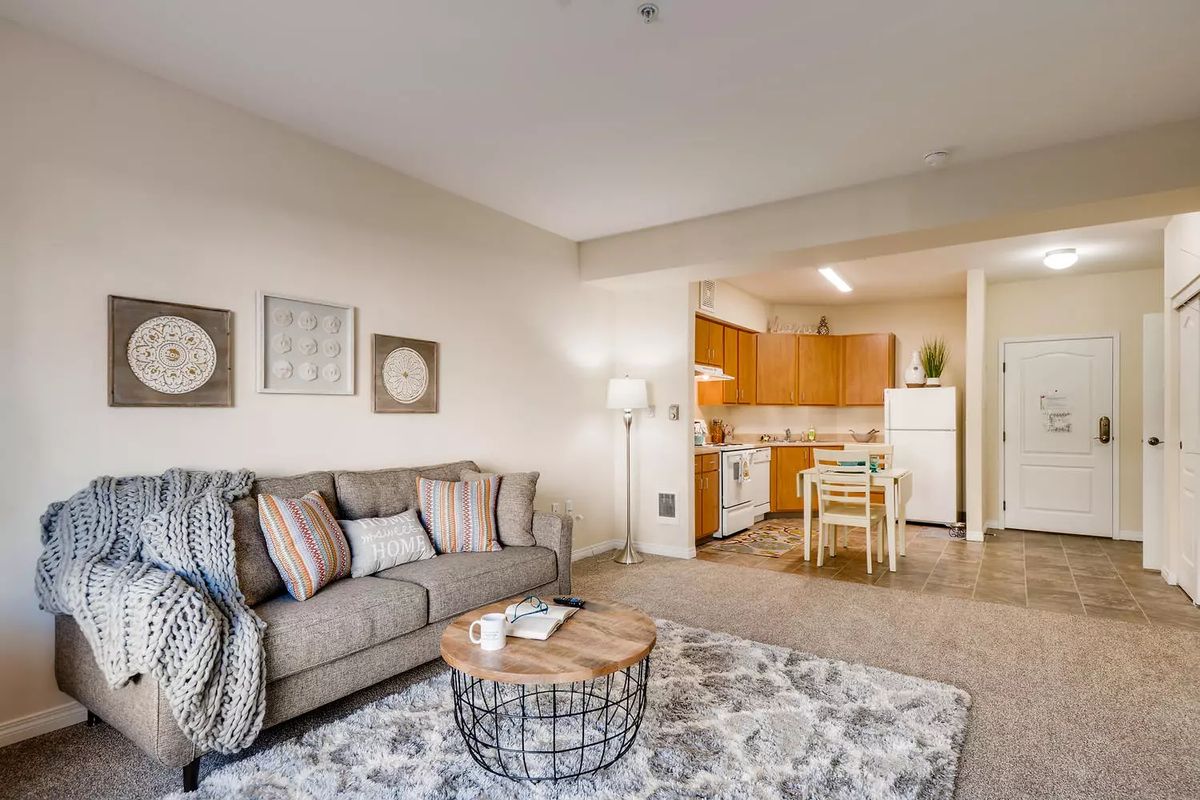 A cozy living space featuring a comfortable sofa and a small dining area adjacent to the kitchen.