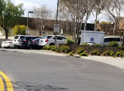 A view of a parking lot with several cars parked and a building in the background.