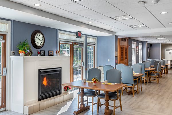 A cozy living and dining area featuring a fireplace, tables with chairs, and large windows.