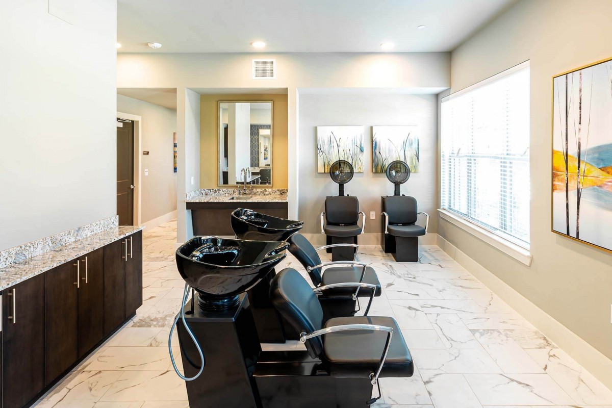 A modern salon interior featuring hair wash stations and comfortable seating, illuminated by bright natural light.