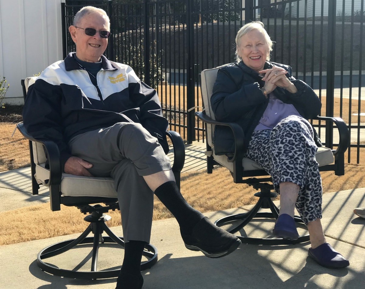 An elderly couple relaxing on chairs outdoors on a sunny day.