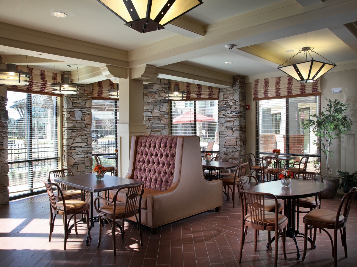 A cozy cafe interior with booth and table seating, featuring large windows allowing natural light to fill the space.