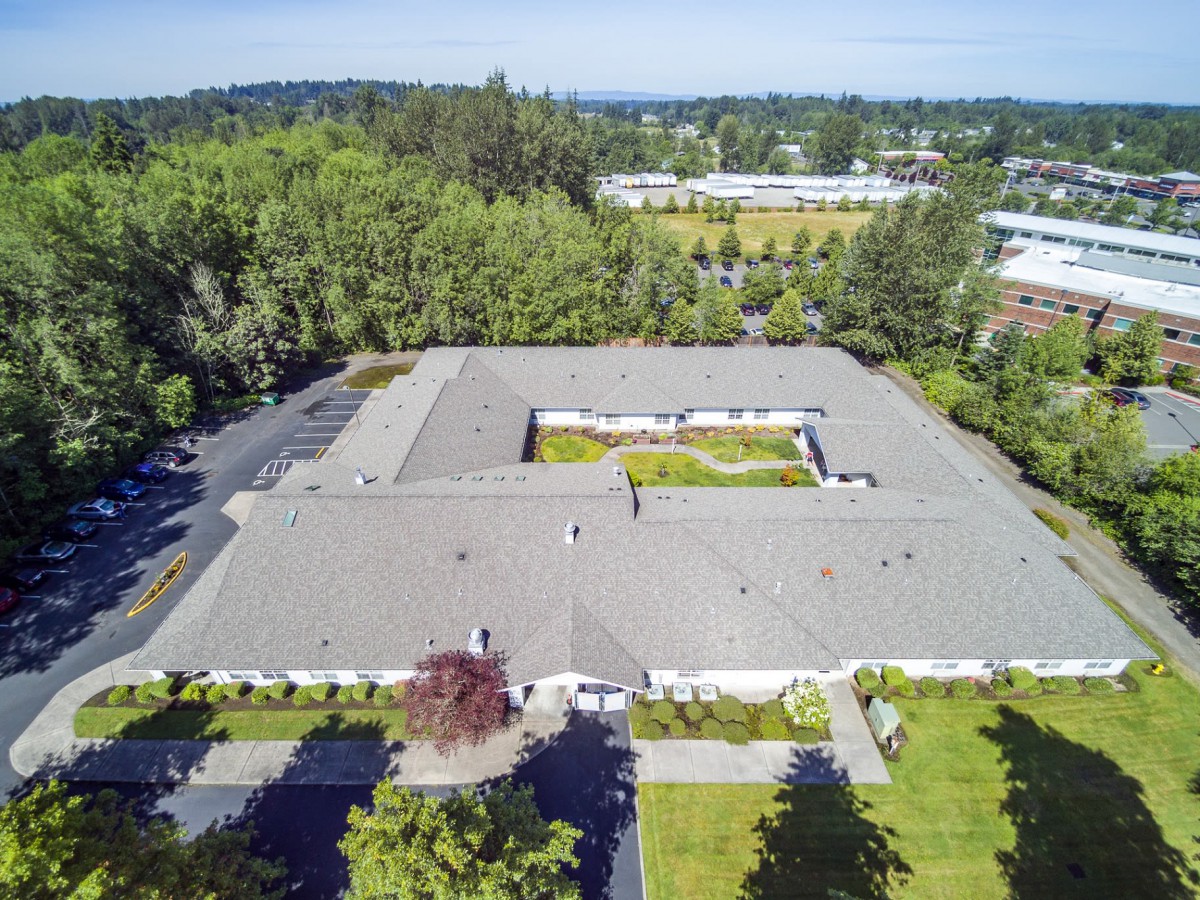 Aerial view of a large building with a central courtyard surrounded by trees and greenery.