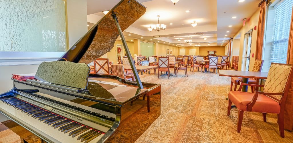 An elegant dining room featuring a grand piano and stylish seating arrangements.