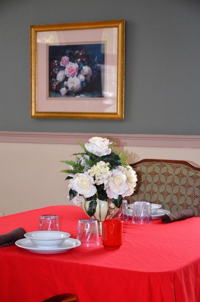 A dining table elegantly set with white flowers and framed artwork on the wall.