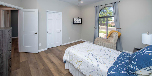 A cozy and modern bedroom featuring light-colored walls and wooden flooring.