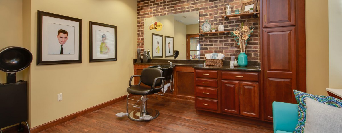 A cozy barber shop interior with a vintage-style barber chair, brick wall, and neatly organized shelves.