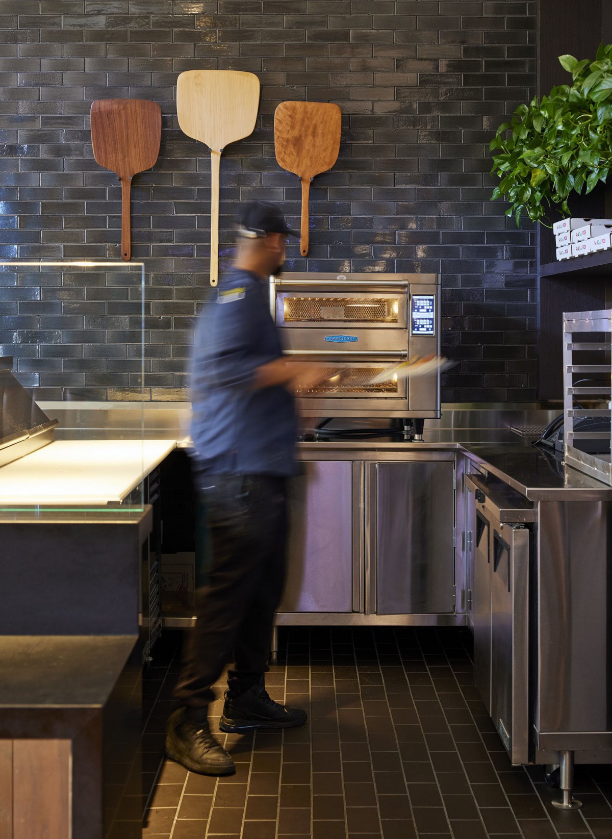 A chef is preparing food in a modern restaurant kitchen with a pizza oven.