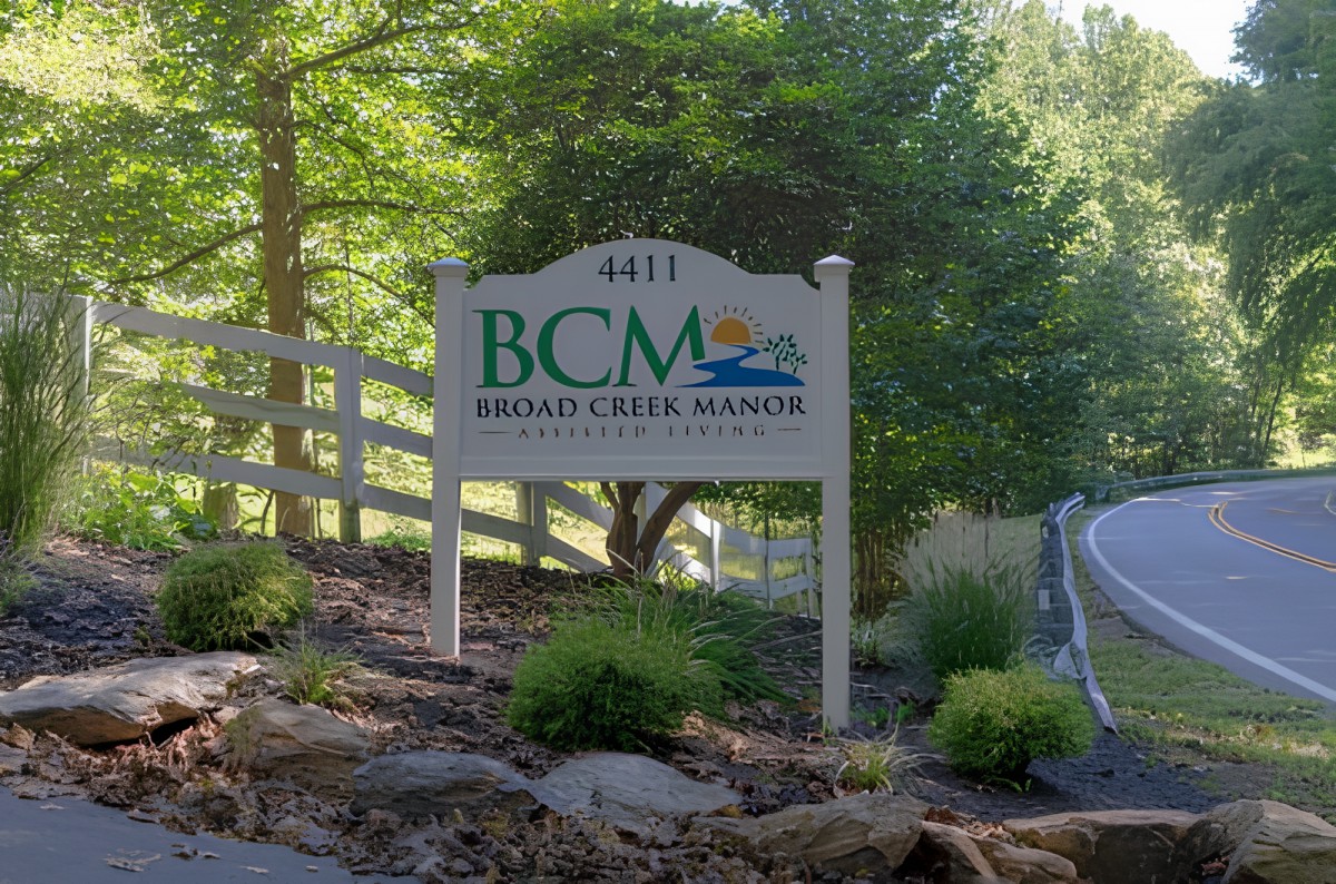 Entrance sign for Bridal Creek Marina surrounded by trees and greenery.