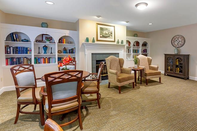 A cozy living area featuring a fireplace, bookshelves, and comfortable chairs around a table.