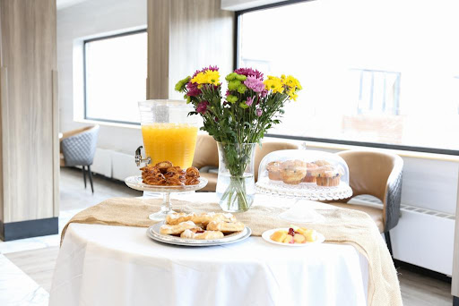 A beautifully arranged breakfast table featuring fresh flowers, pastries, and a refreshing glass of fruit juice.