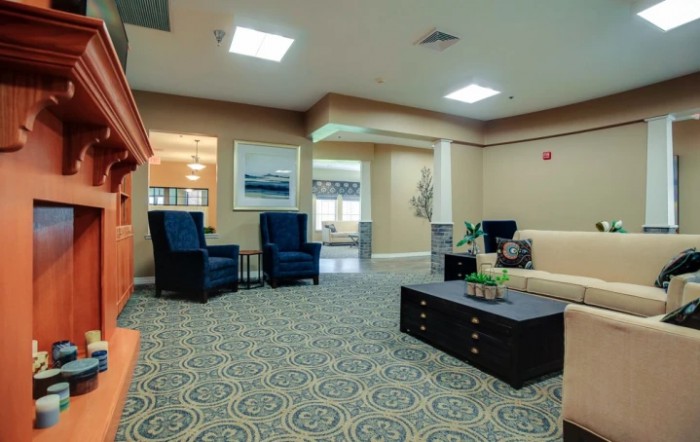 A cozy living room with seating arrangements, a decorative carpet, and warm lighting.