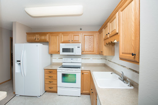 A modern kitchen featuring wooden cabinets, a countertop, and essential appliances.