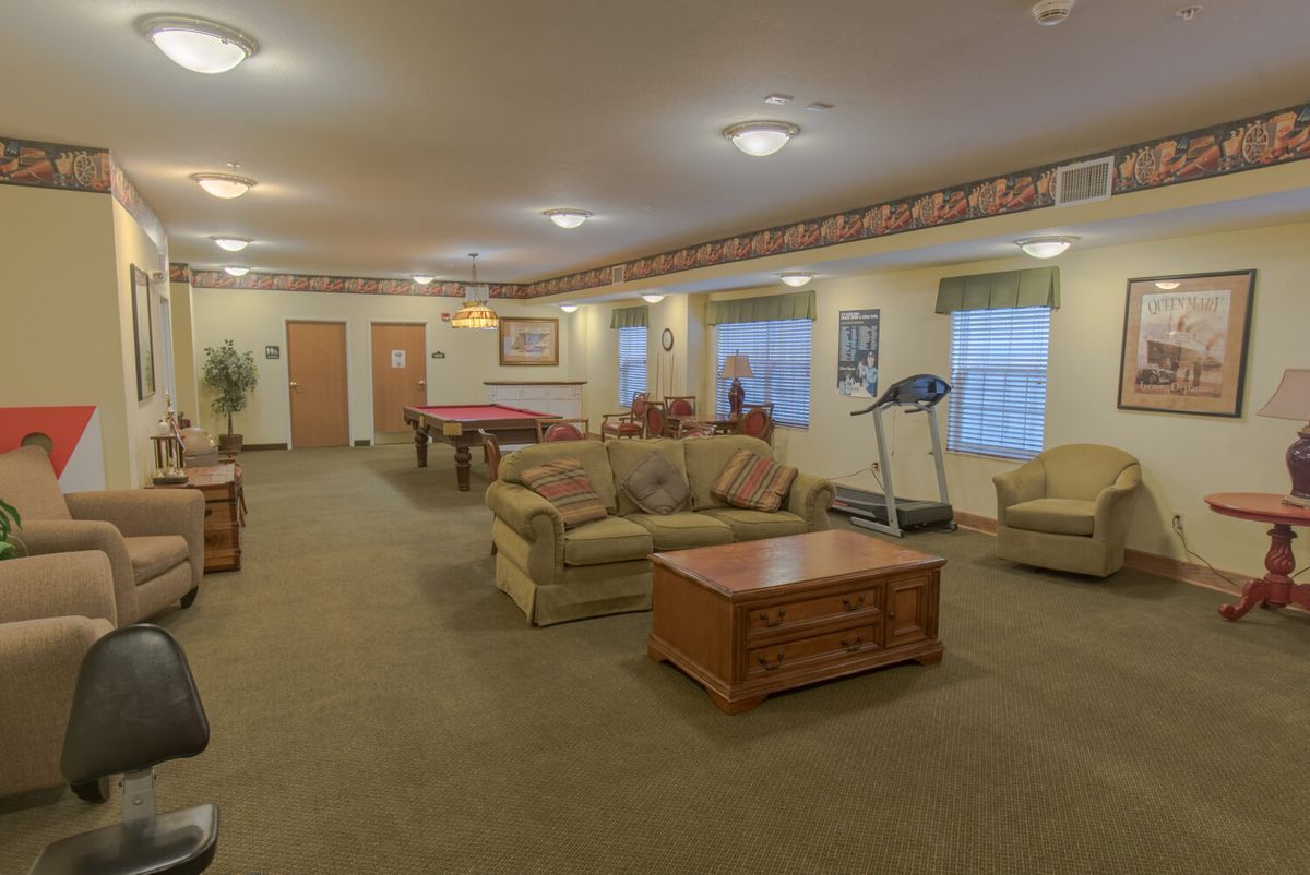 A spacious living room with a pool table, treadmill, and cozy seating area.