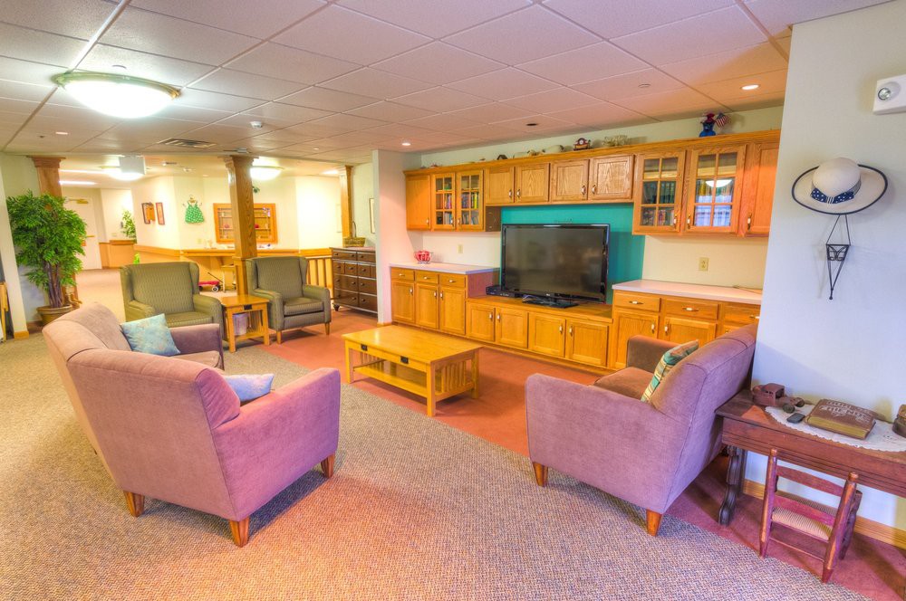 A cozy living room with comfortable seating and a large TV surrounded by wooden cabinetry.