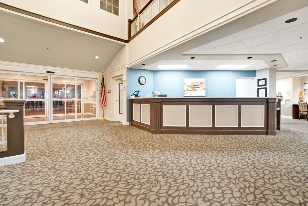 A spacious hotel lobby with a reception desk and carpeted floor.