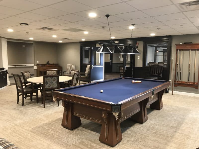 A spacious recreation room featuring a blue felt pool table.