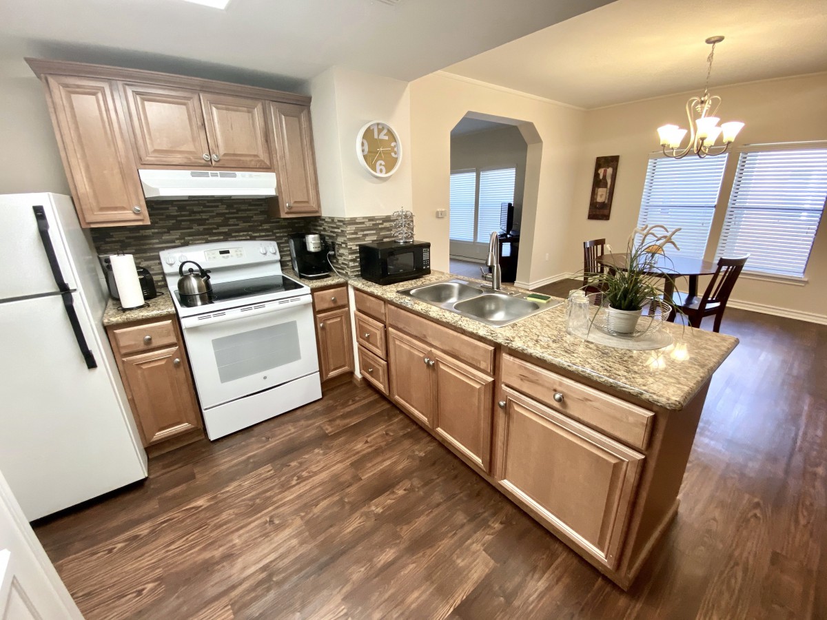 A modern kitchen with wooden cabinets, granite countertops, and stainless steel appliances.