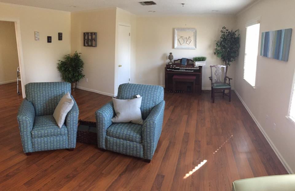 A cozy living room with two striped armchairs and a piano on a wooden floor.