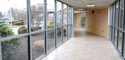 A spacious hallway featuring large windows that allow natural light to illuminate the interior, complemented by indoor greenery.