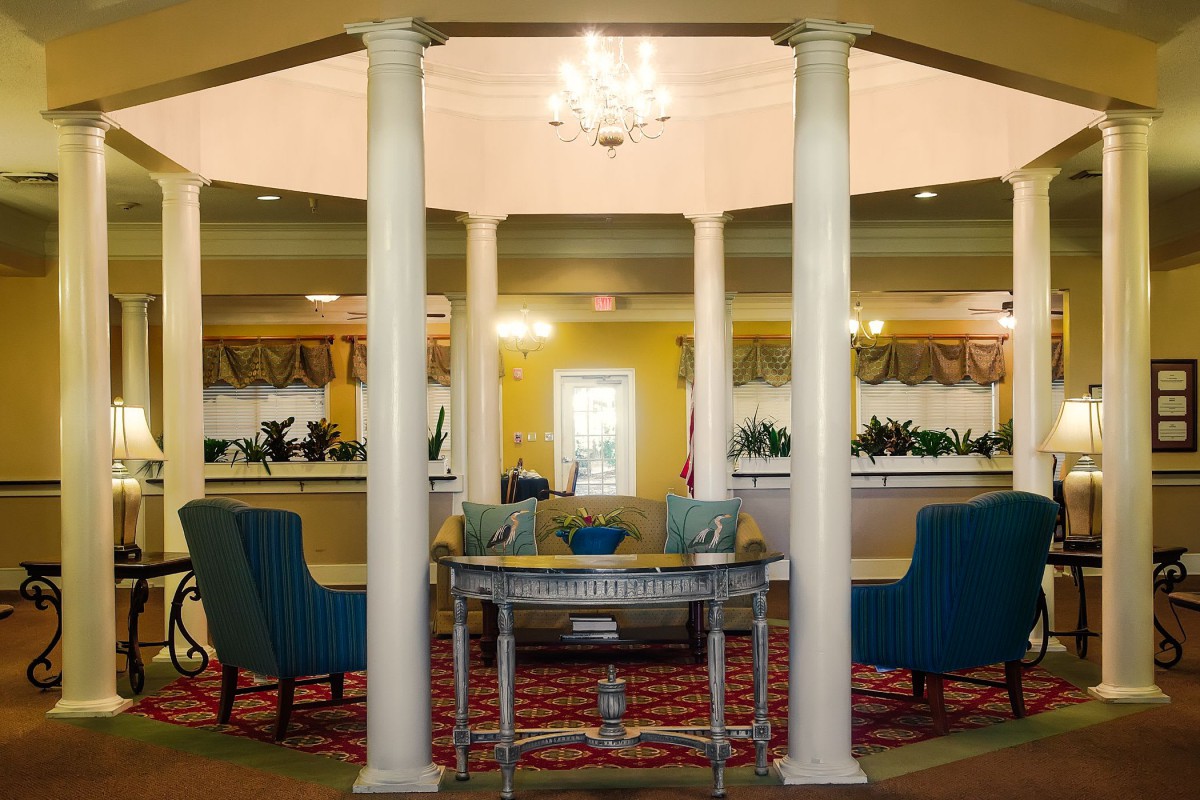 A well-decorated lobby area featuring columns, elegant furniture, and a chandelier.