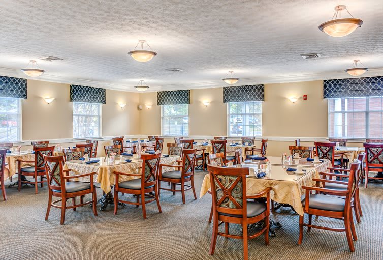 A well-lit dining room with multiple tables and chairs arranged neatly.