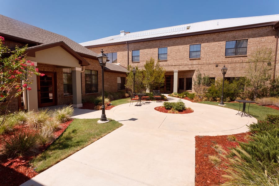 A well-maintained courtyard area with pathways leading to a brick building.