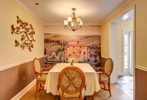 A beautifully designed dining room featuring a scenic wall mural, elegant chandelier, and a tasteful table setting.