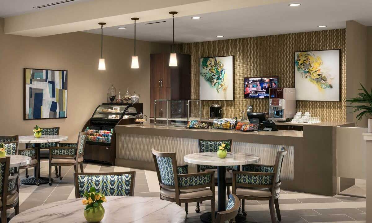 A cozy cafe interior with a counter, tables, and chairs.