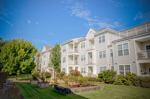 A beautiful apartment complex with lush landscaping under a clear blue sky.