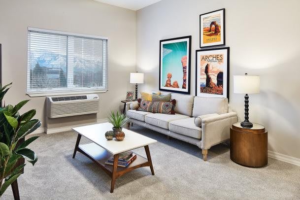 A modern living room featuring a beige sofa, stylish coffee table, and vibrant wall art.