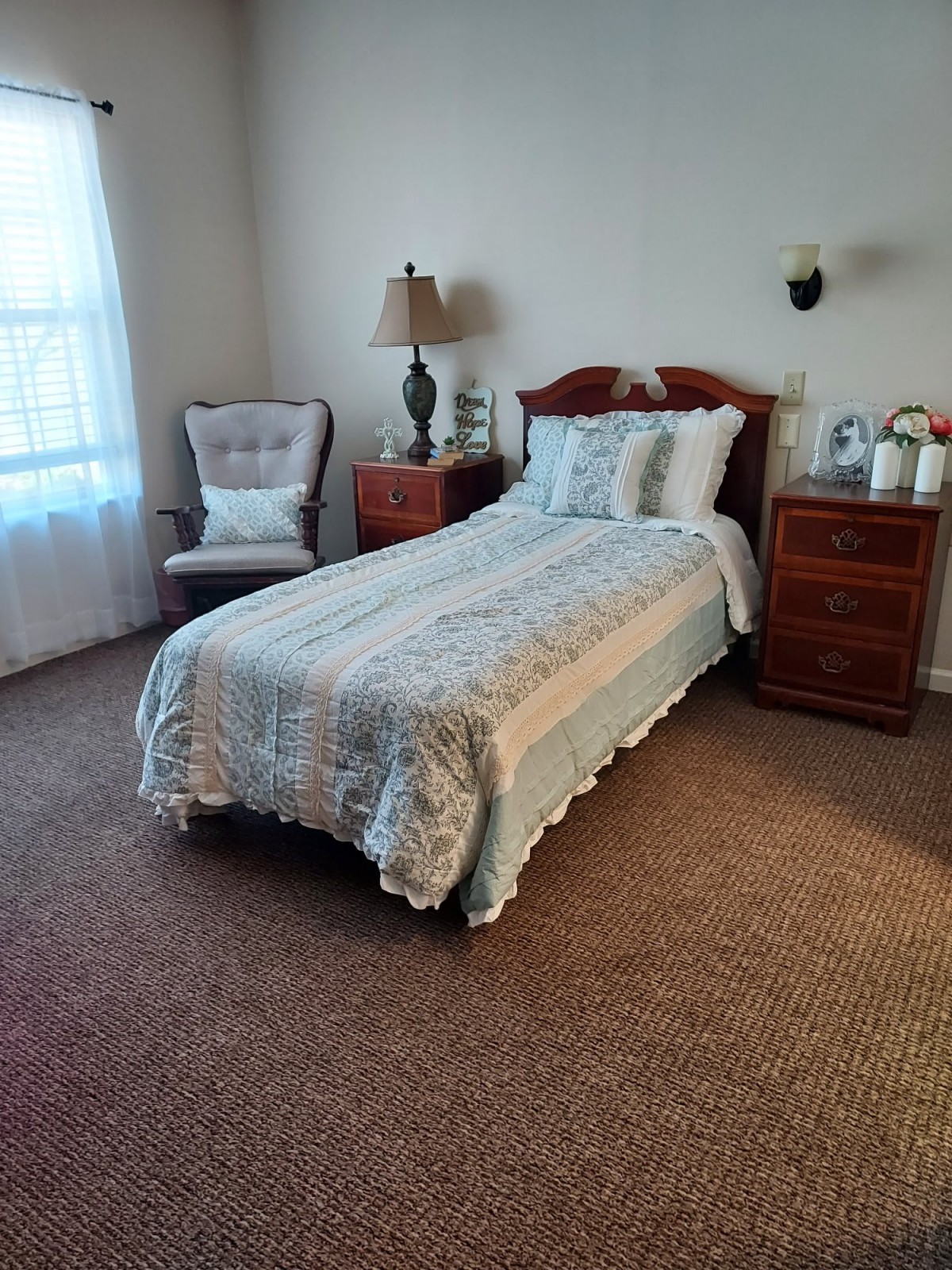 A cozy bedroom with a single bed, comfortable chair, and wooden furniture.