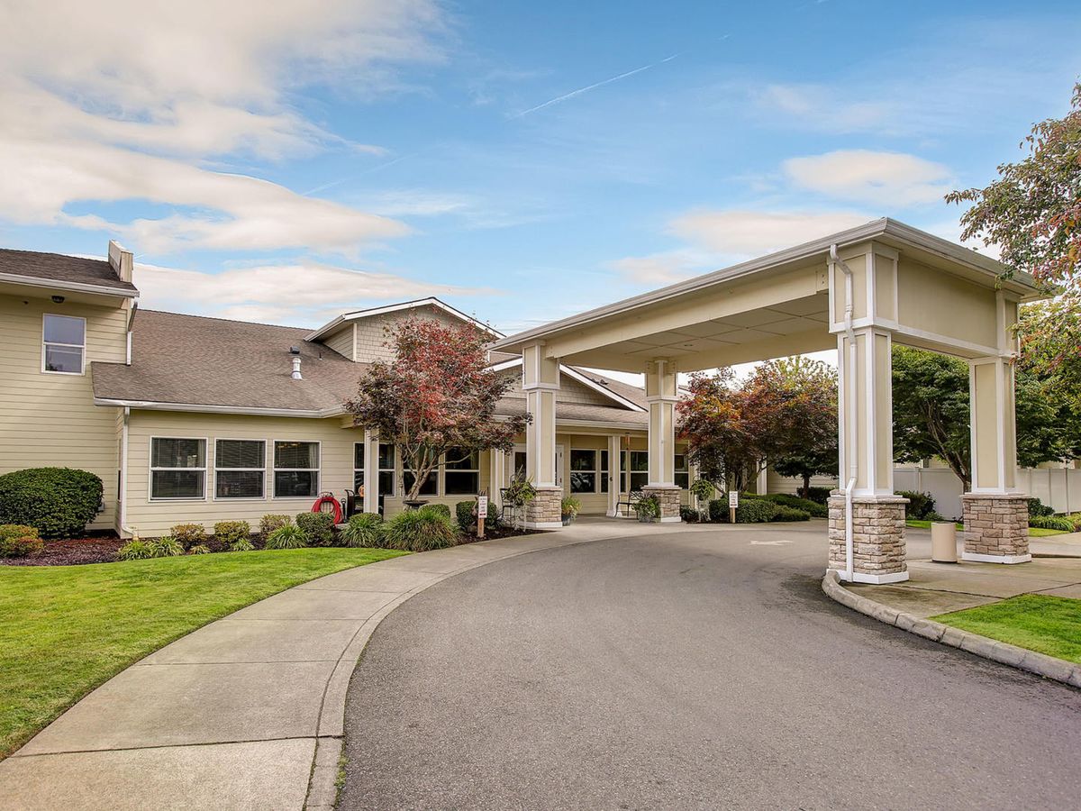 An inviting building entrance with a covered driveway surrounded by greenery.