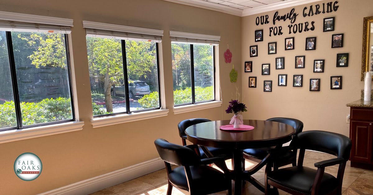 A cozy dining room with a round table surrounded by chairs, adorned with family photos and bright natural light streaming through the windows.